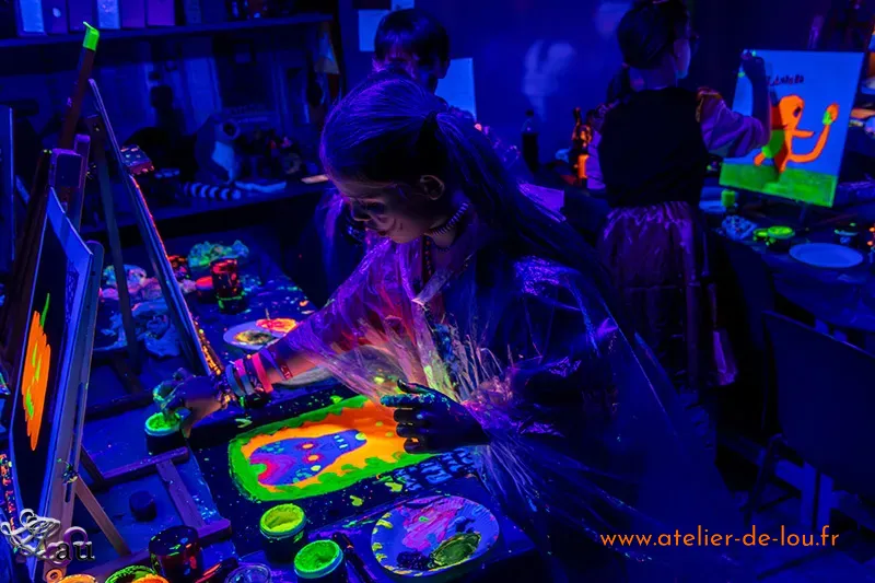 Enfants participant à un anniversaire peinture dans le noir à Reims avec des couleurs fluorescentes.